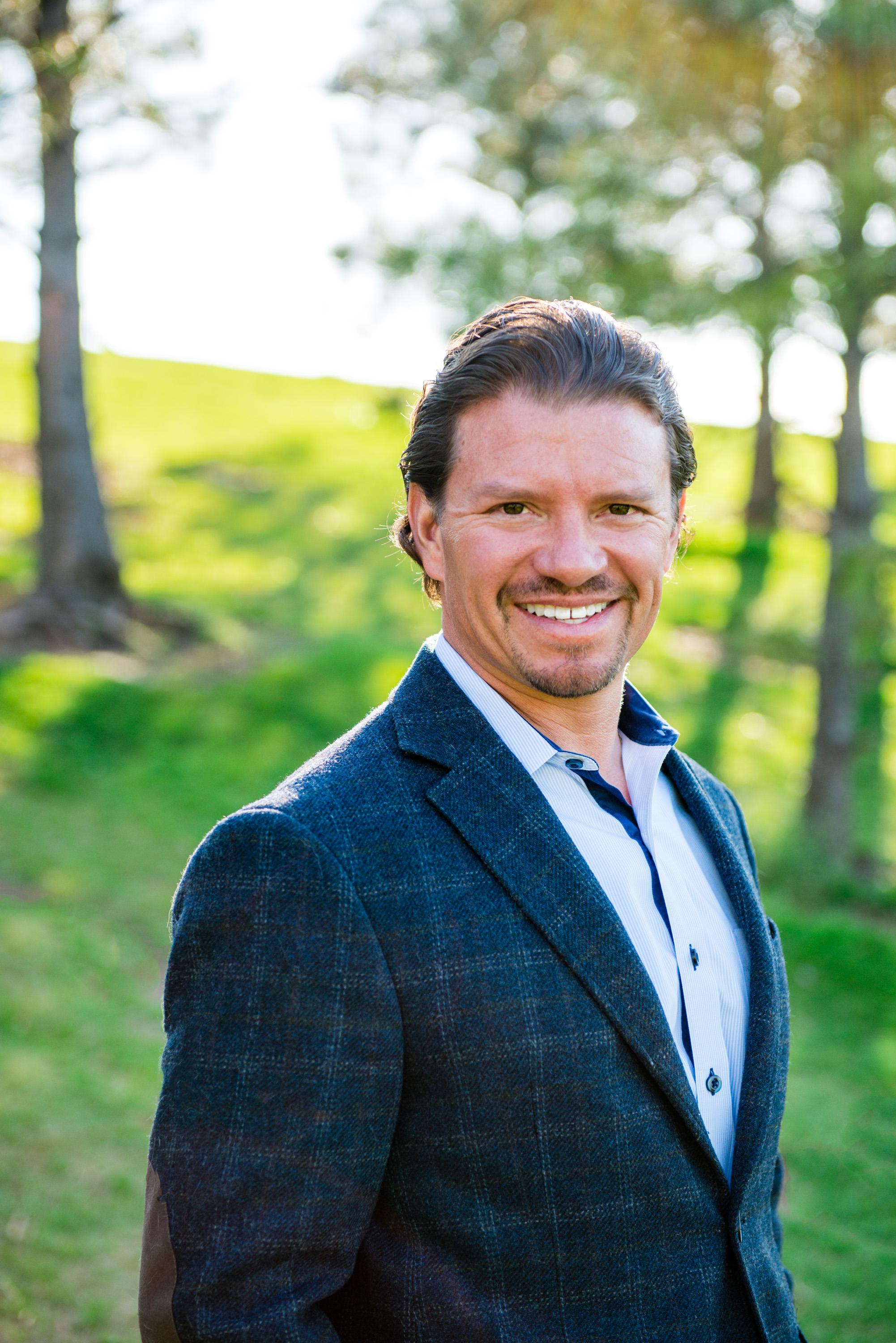 a man wearing a suit and tie smiling at the camera